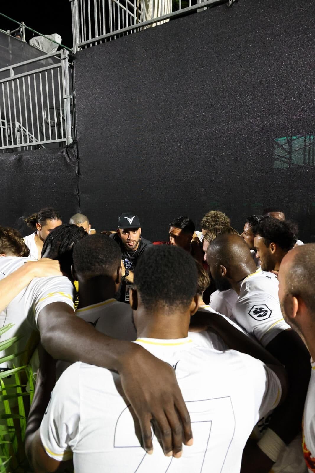 Night-time team huddle around Coach Rafaz.